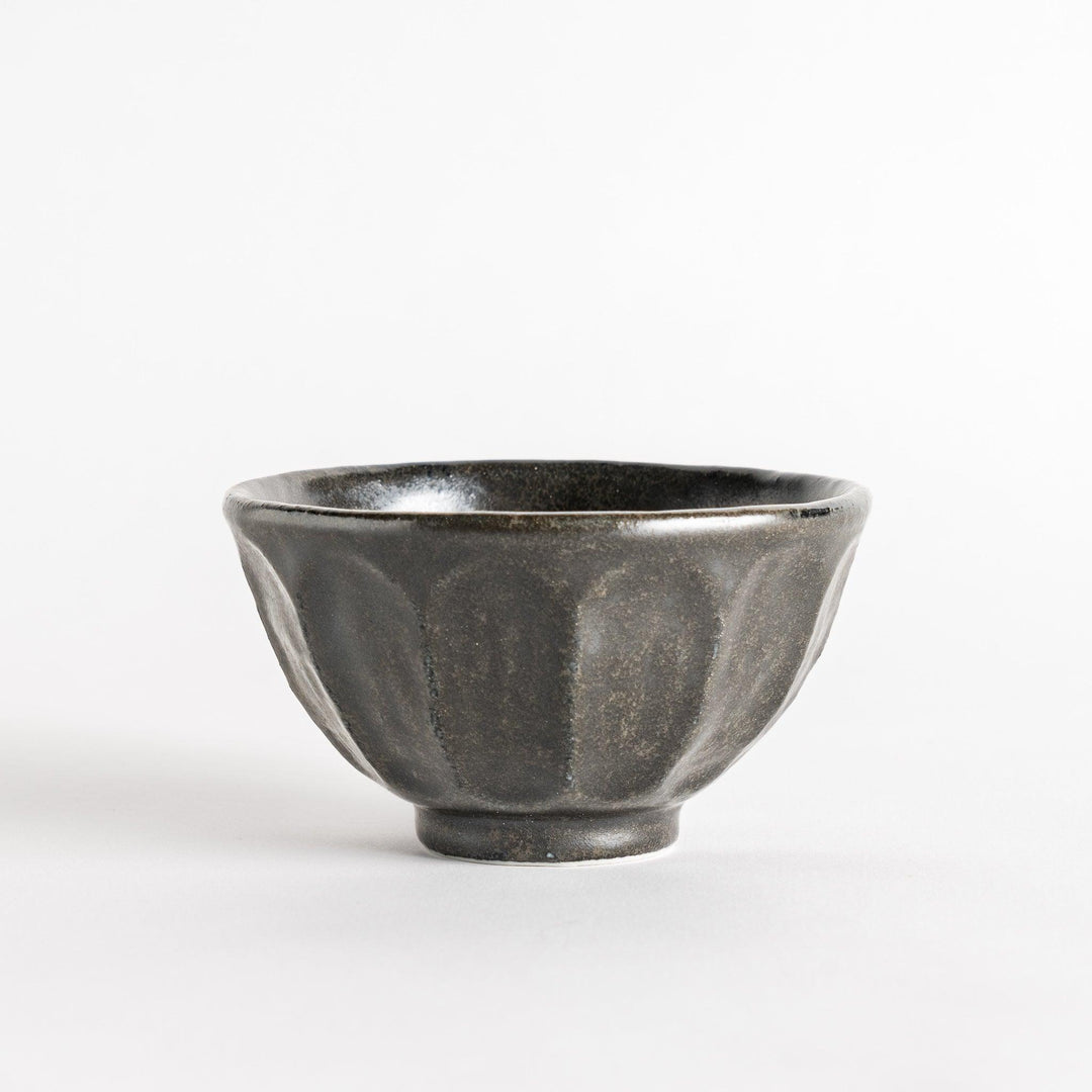 A minimalist ceramic mug with a textured, faceted finish. Available in black or white.