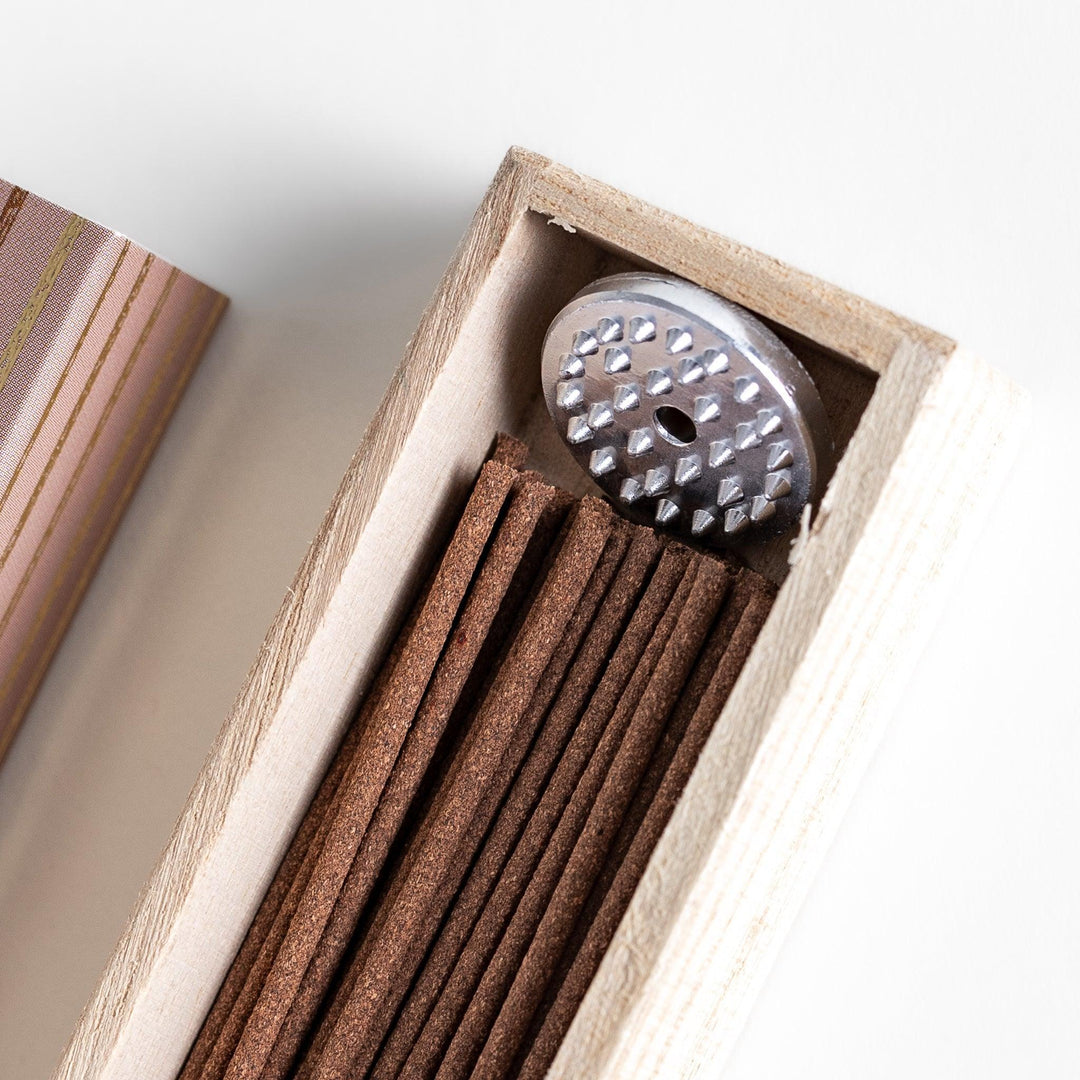 Brown incense sticks in a wooden box with beige packaging and white circular patterns evoking coffee aroma.