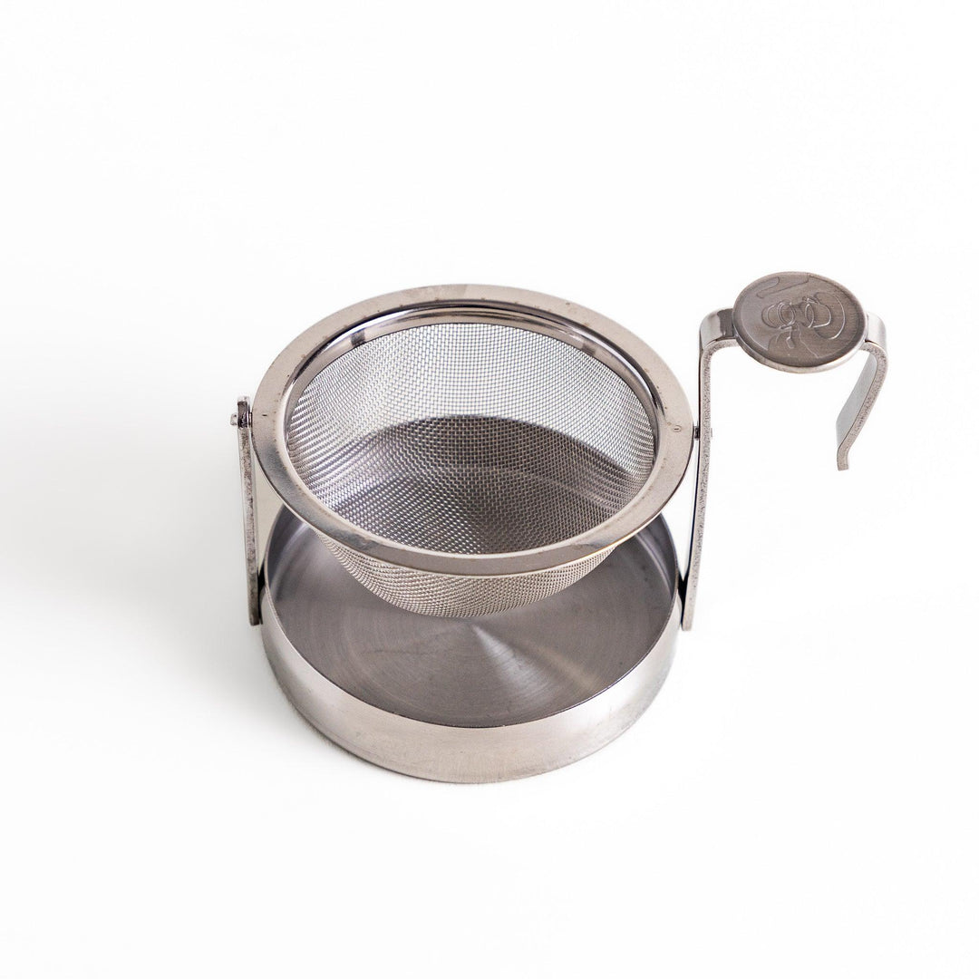 Japanese stainless steel rotating tea strainer with fine mesh and drip tray for easy loose leaf brewing.