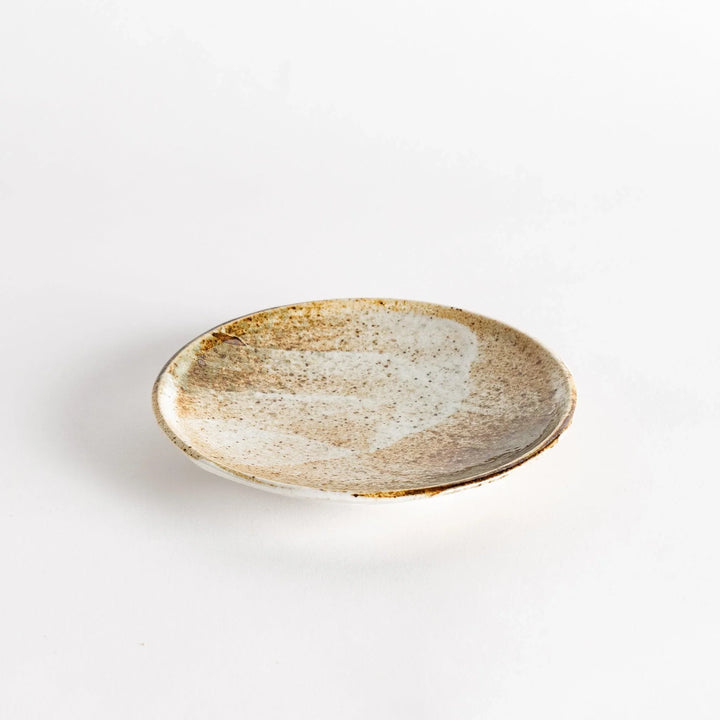 A small dessert plate with a speckled cream and brown glaze, featuring an organic, earthy design.