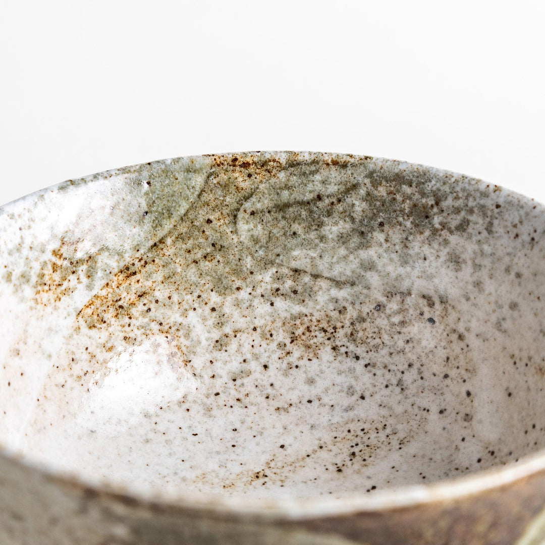 A ceramic bowl with a speckled cream and brown glaze, showcasing an earthy and organic finish.