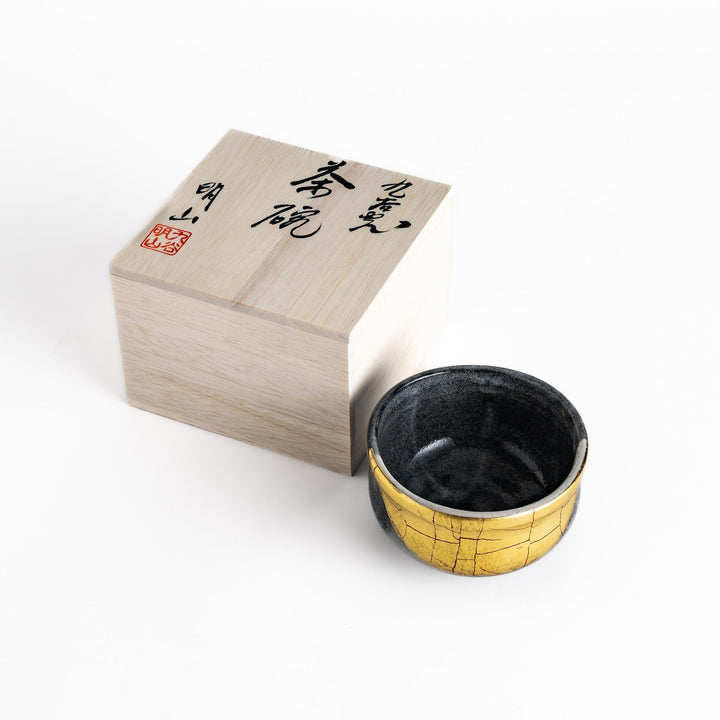 Black matcha bowl with gold crackle glaze in wooden box perfect for elegant Japanese tea ceremonies.