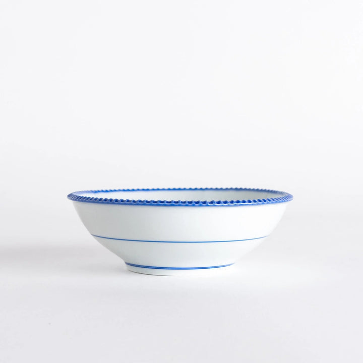 Side view of the cereal bowl displaying its smooth curves and blue scalloped detailing.