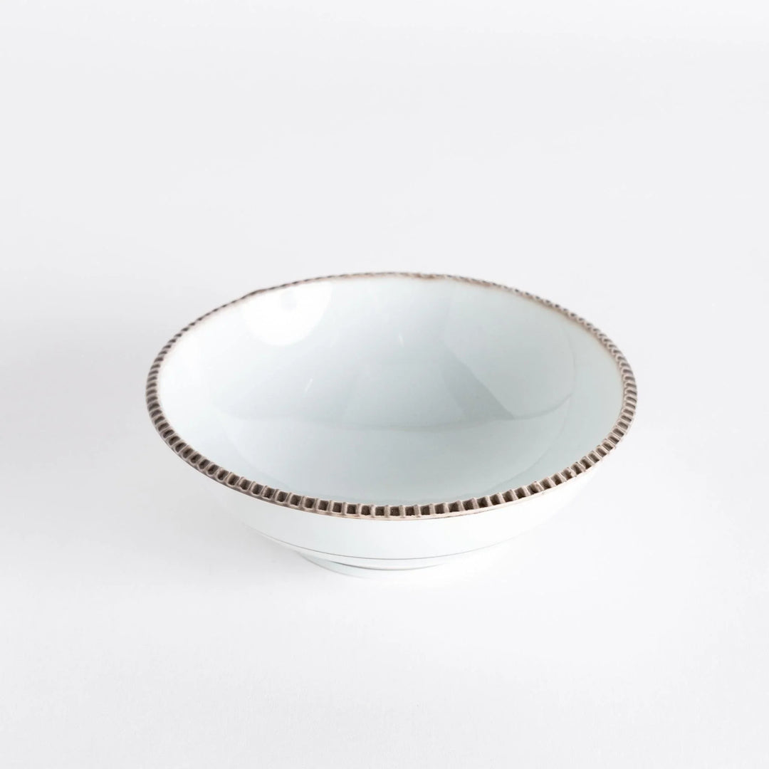 Top view of a cereal bowl with a smooth white interior and a rustic brown scalloped rim.