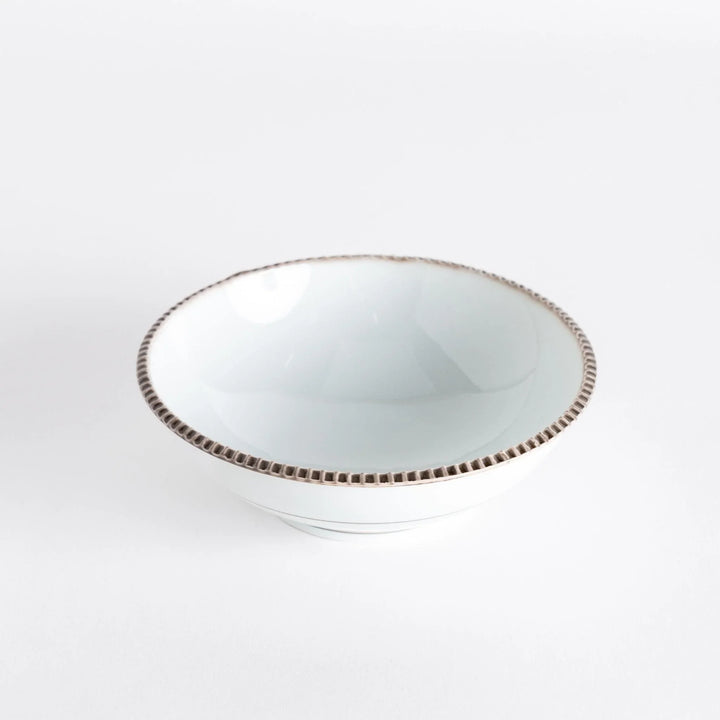 Top view of a cereal bowl with a smooth white interior and a rustic brown scalloped rim.