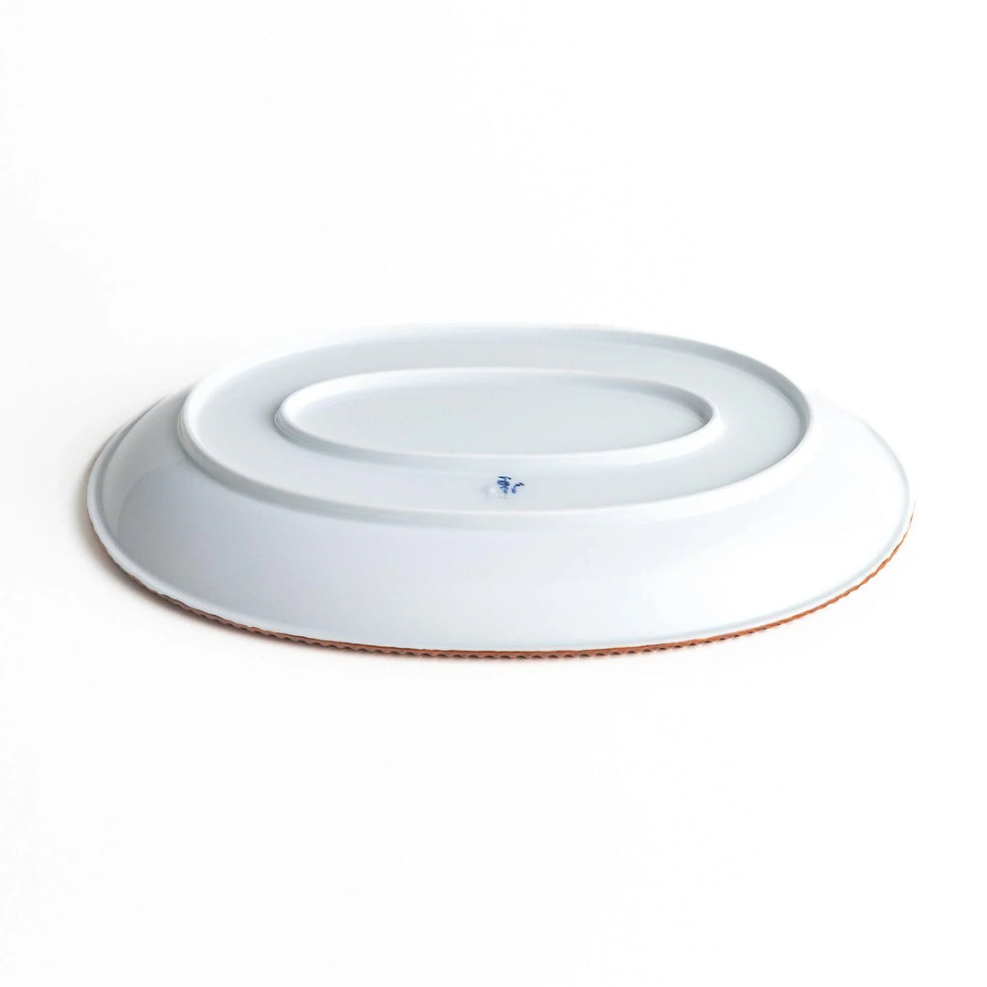 An oval-shaped white dinner plate with a rustic scallop-edged design. The border comes in blue, brown, and olive.