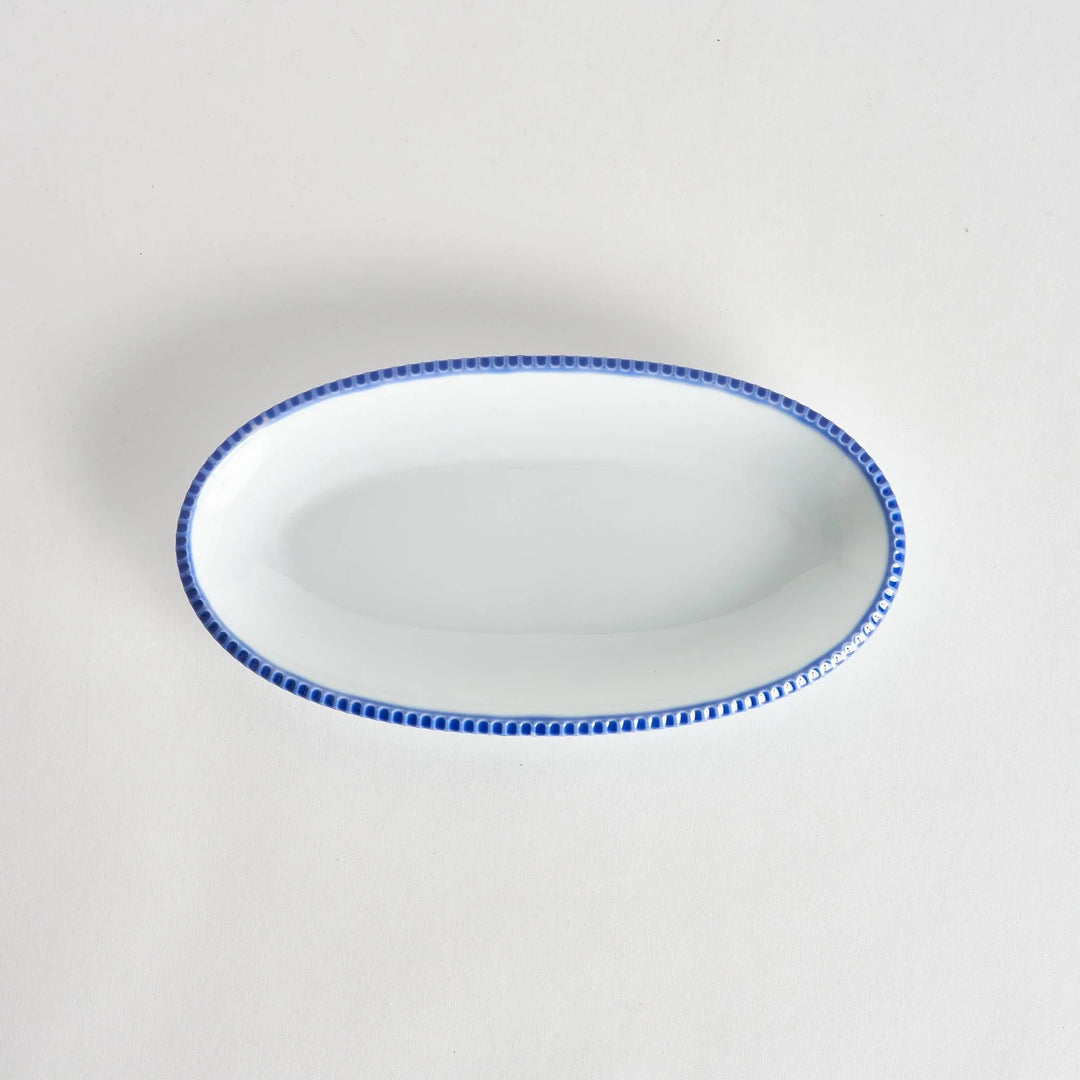 Top-down view of an oval salad platewith rustic scalloped edges and a blue beaded rim, showcasing its simple, elegant design.