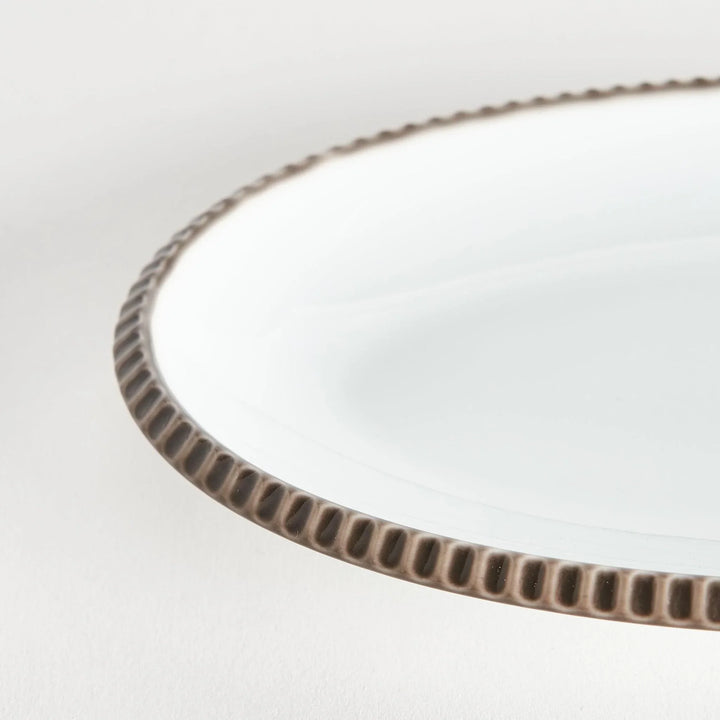Close-up of the olive-colored scalloped edge of the oval salad plate, highlighting its natural design.