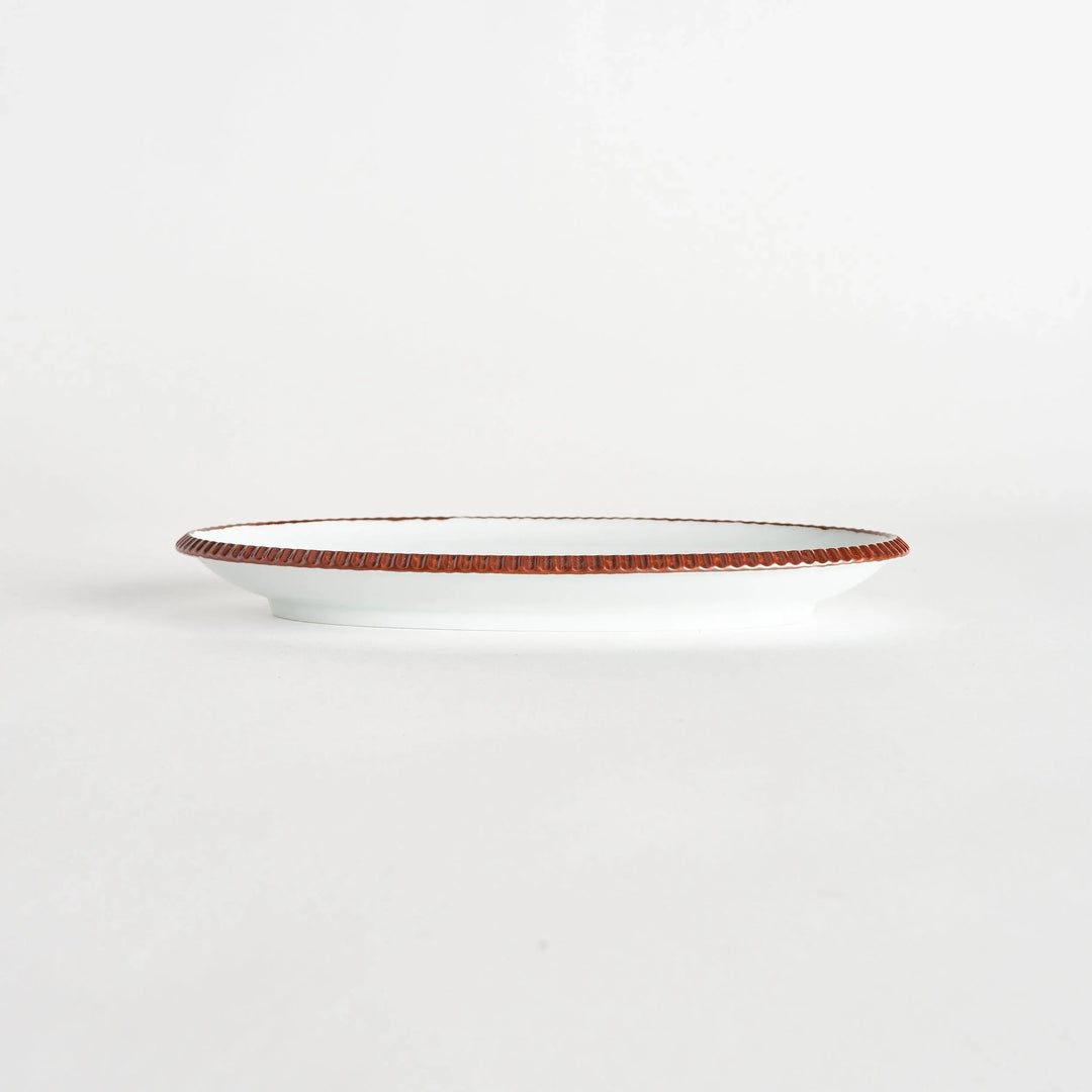 Side view of an oval salad plate featuring a warm brown-colored scalloped edge.
