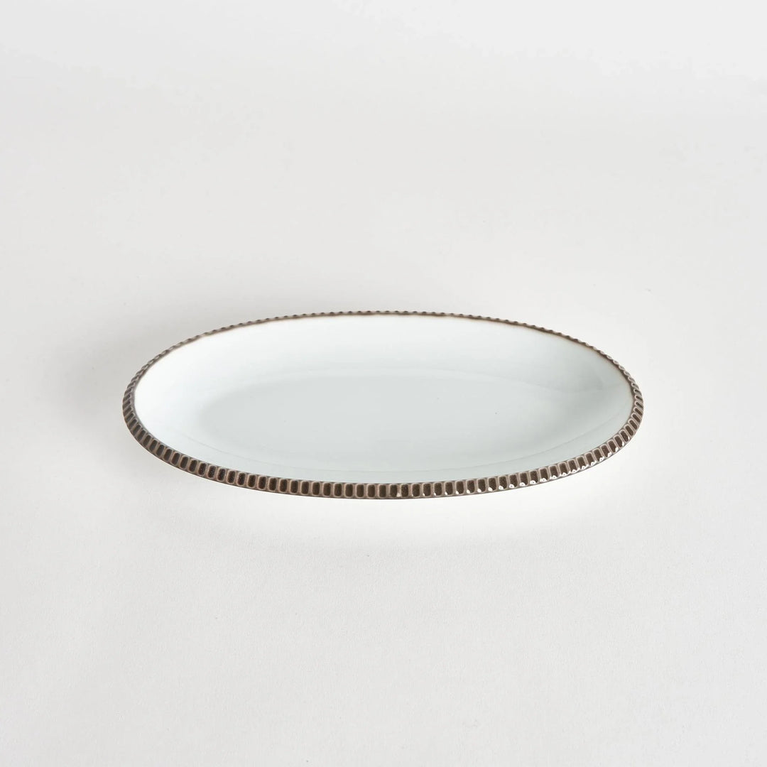 Angled view of an oval salad plate with an olive-colored scalloped edge.