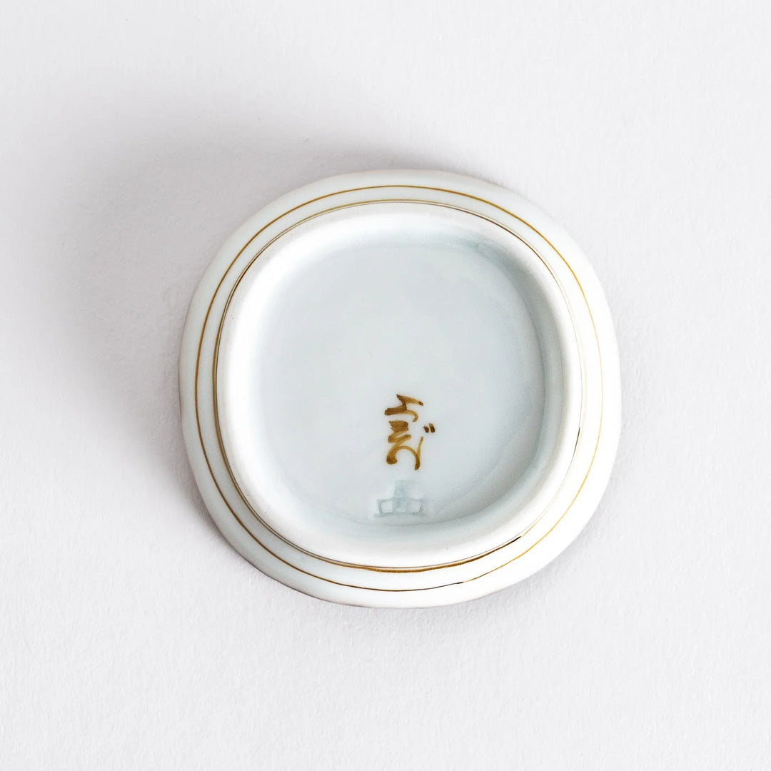 Close-up view of the interior of a small oval sauce dish, highlighting its smooth surface and brown dotted rim.