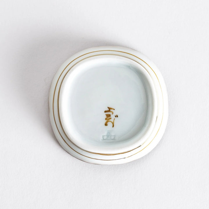 Close-up view of the interior of a small oval sauce dish, highlighting its smooth surface and brown dotted rim.