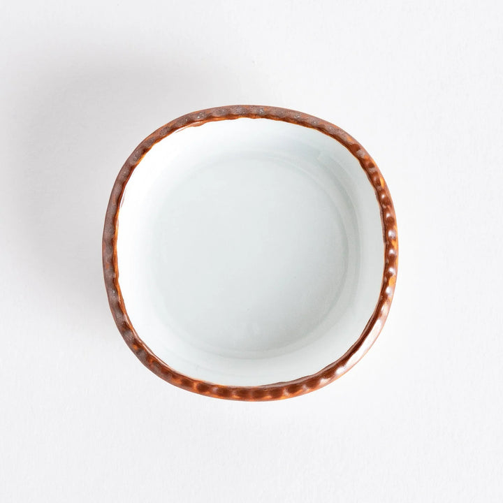 Underside view of a small oval sauce dish, revealing its smooth base and manufacturer mark.