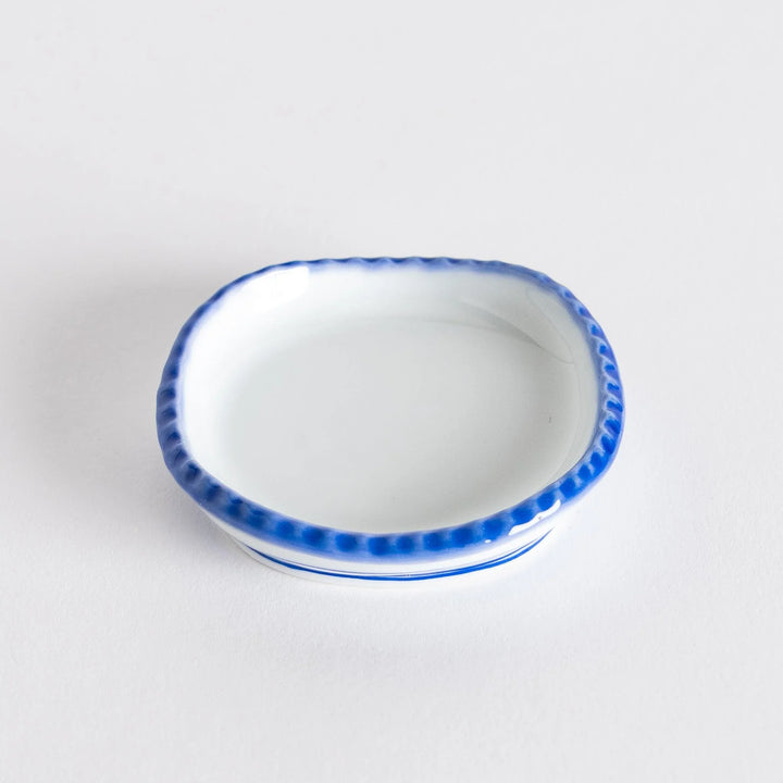 Angle view of the oval sauce dish displaying the subtle curvature and rustic finish.