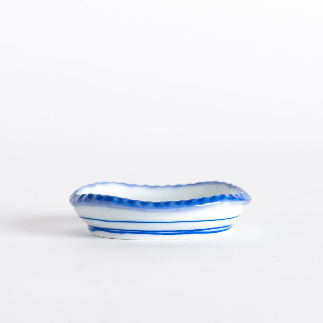 Side view of an oval sauce dish with scalloped edges, showcasing its unique rustic design.