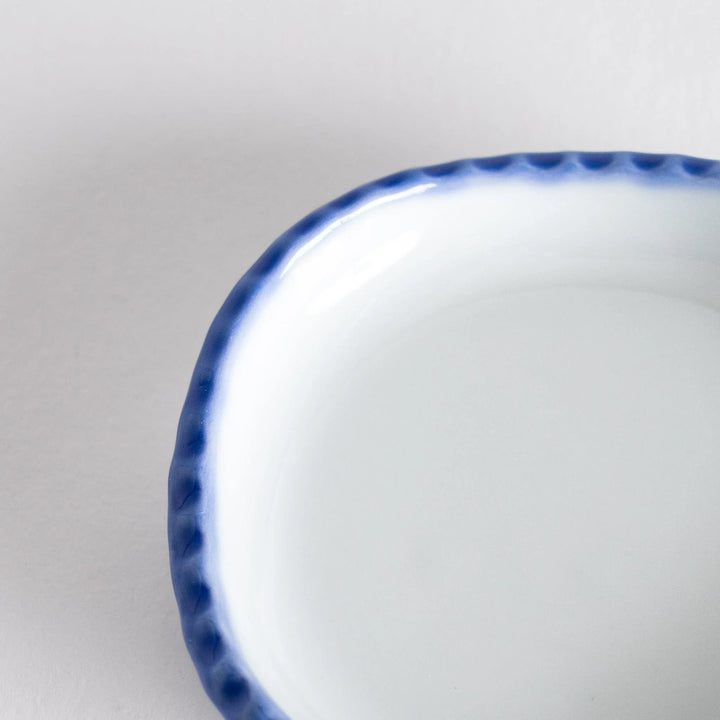 Close-up of the oval sauce dish, emphasizing the elegant blue border and smooth interior surface.