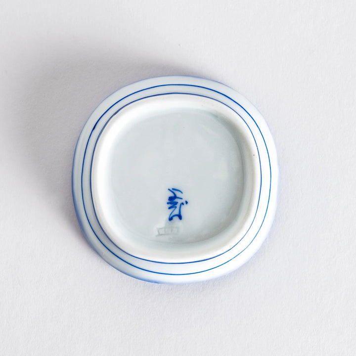 Underside view of a small, square condiment dish displaying smooth surfaces and subtle markings.