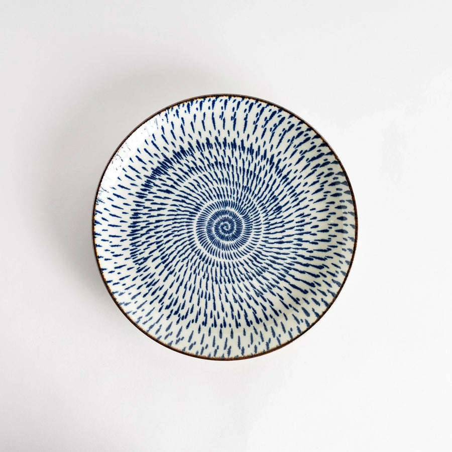 A round dinner plate featuring a striking pattern of blue lines radiating from the center.