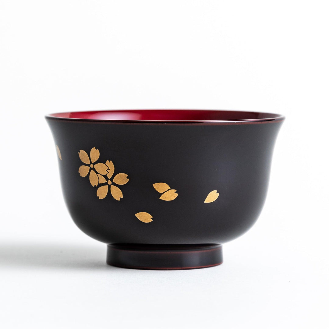 Traditional black lacquer bowl with red interior and gold cherry blossom motif.