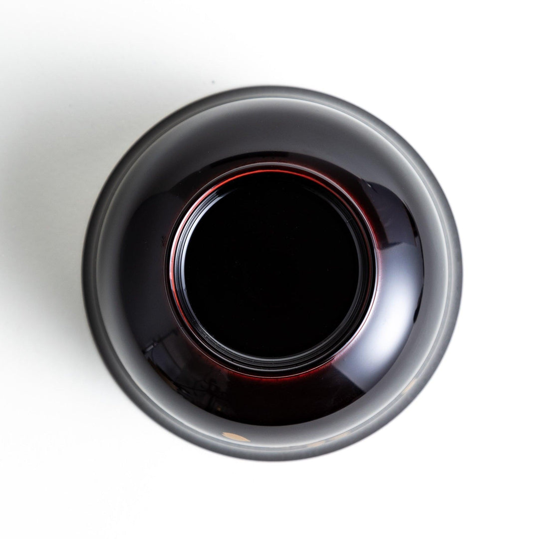 Traditional black lacquer bowl with red interior and gold cherry blossom motif.