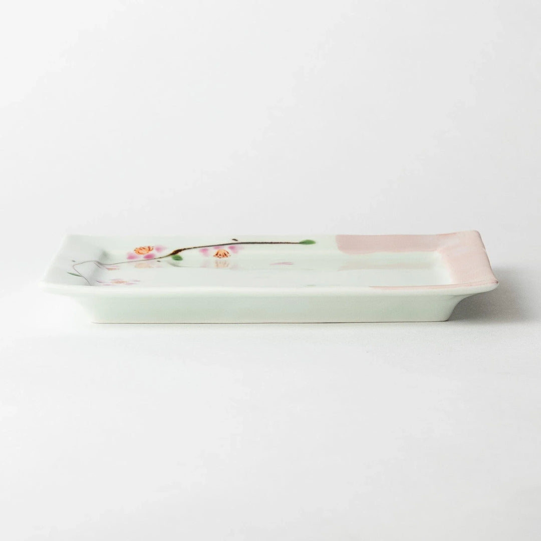 Dessert plate viewed from the side, displaying the square shape and soft pink border with floral details.