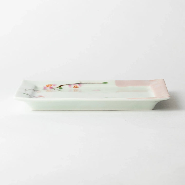 Dessert plate viewed from the side, displaying the square shape and soft pink border with floral details.