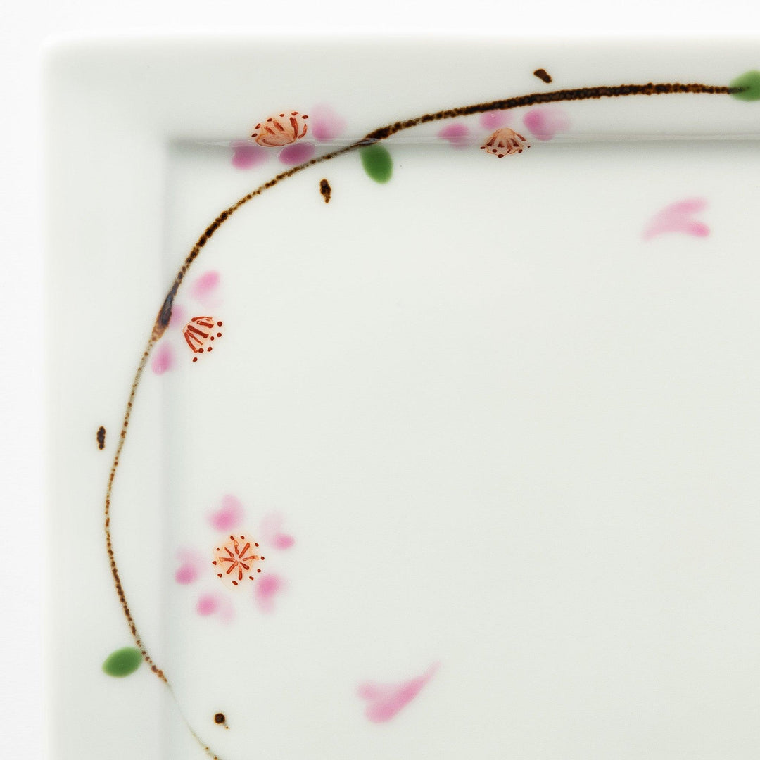 Close-up of the cherry blossom pattern on the dessert plate, focusing on the soft pink petals and green leaves.