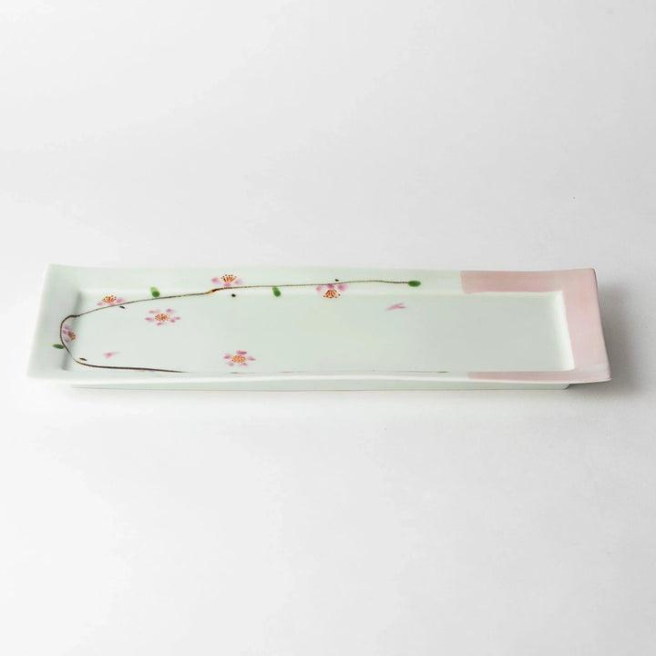 Rectangular plate with cherry blossom design, captured at an angle, highlighting its soft pink and floral details.