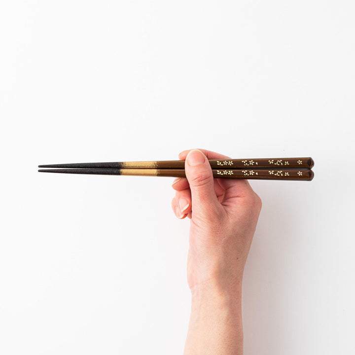Red and brown lacquered chopsticks with gold cherry blossom motifs and elegant gold gradient detailing.