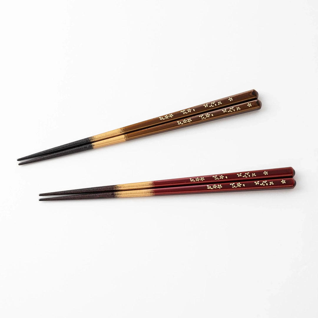 Elegant red and brown lacquered chopsticks adorned with delicate gold cherry blossom motifs, featuring a gradient of gold for added sophistication.