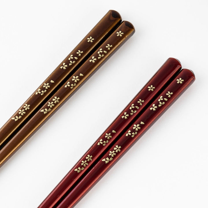 Elegant red and brown lacquered chopsticks adorned with delicate gold cherry blossom motifs, featuring a gradient of gold for added sophistication.