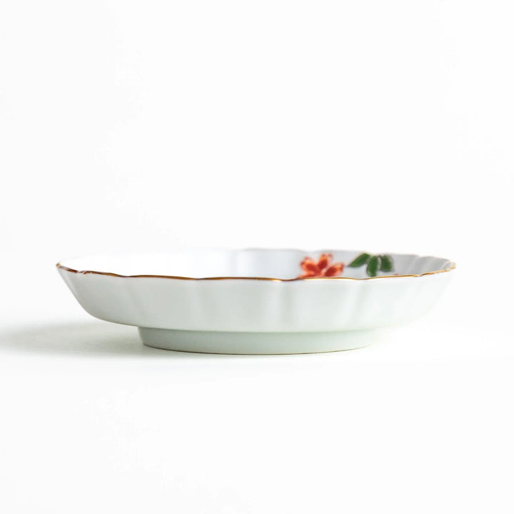 A white ceramic plate adorned with a red floral design and an outline of Mount Fuji in the background.