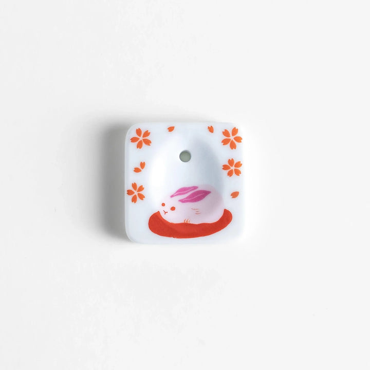 Square ceramic incense holder with sakura rabbit design in pink and red crafted to hold incense with elegance.