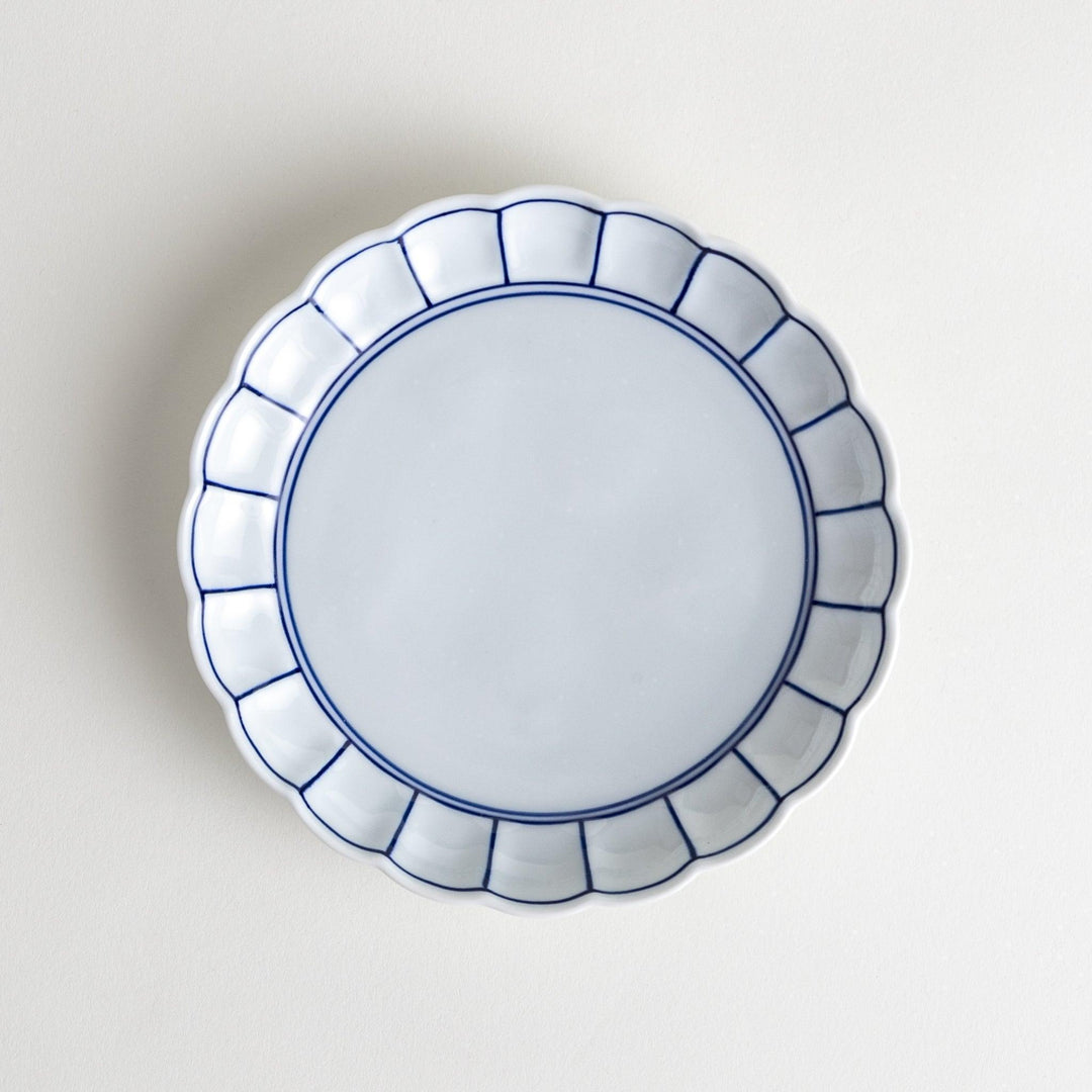 White dessert plate with scalloped edges, outlined in a thin blue or red line.