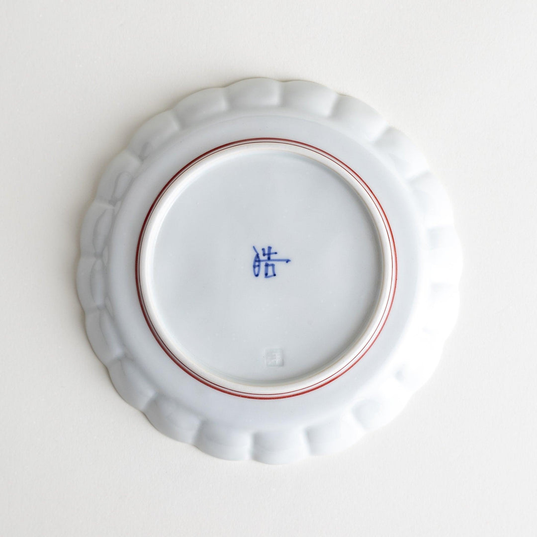White dessert plate with scalloped edges, outlined in a thin blue or red line.