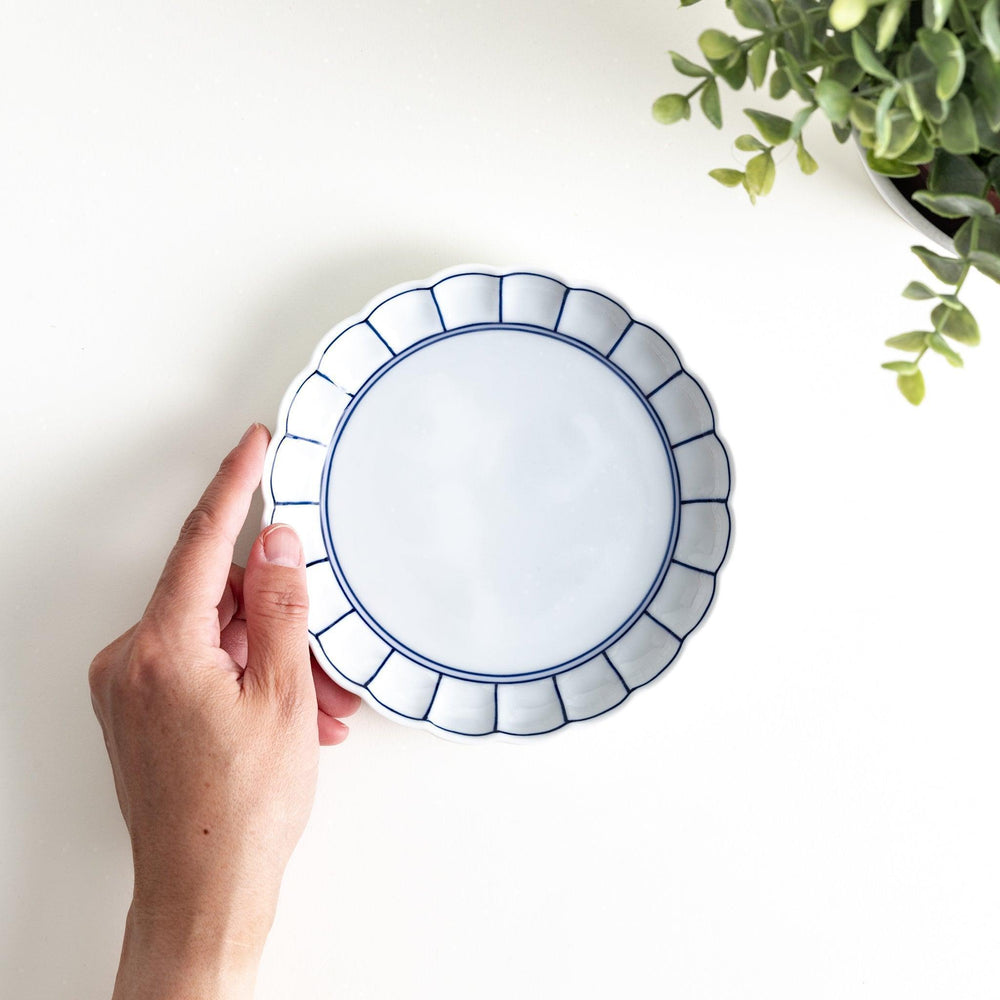 White dessert plate with scalloped edges, outlined in a thin blue or red line.