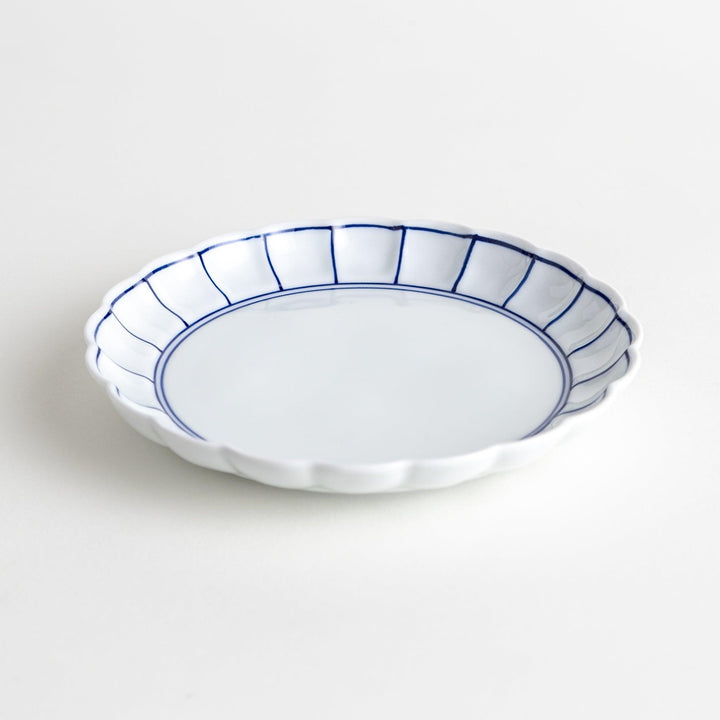 White dessert plate with scalloped edges, outlined in a thin blue or red line.
