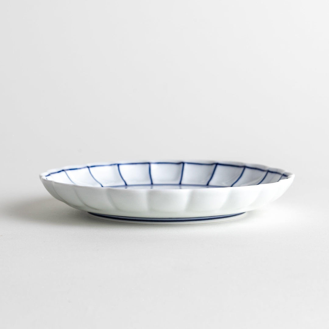White dessert plate with scalloped edges, outlined in a thin blue or red line.