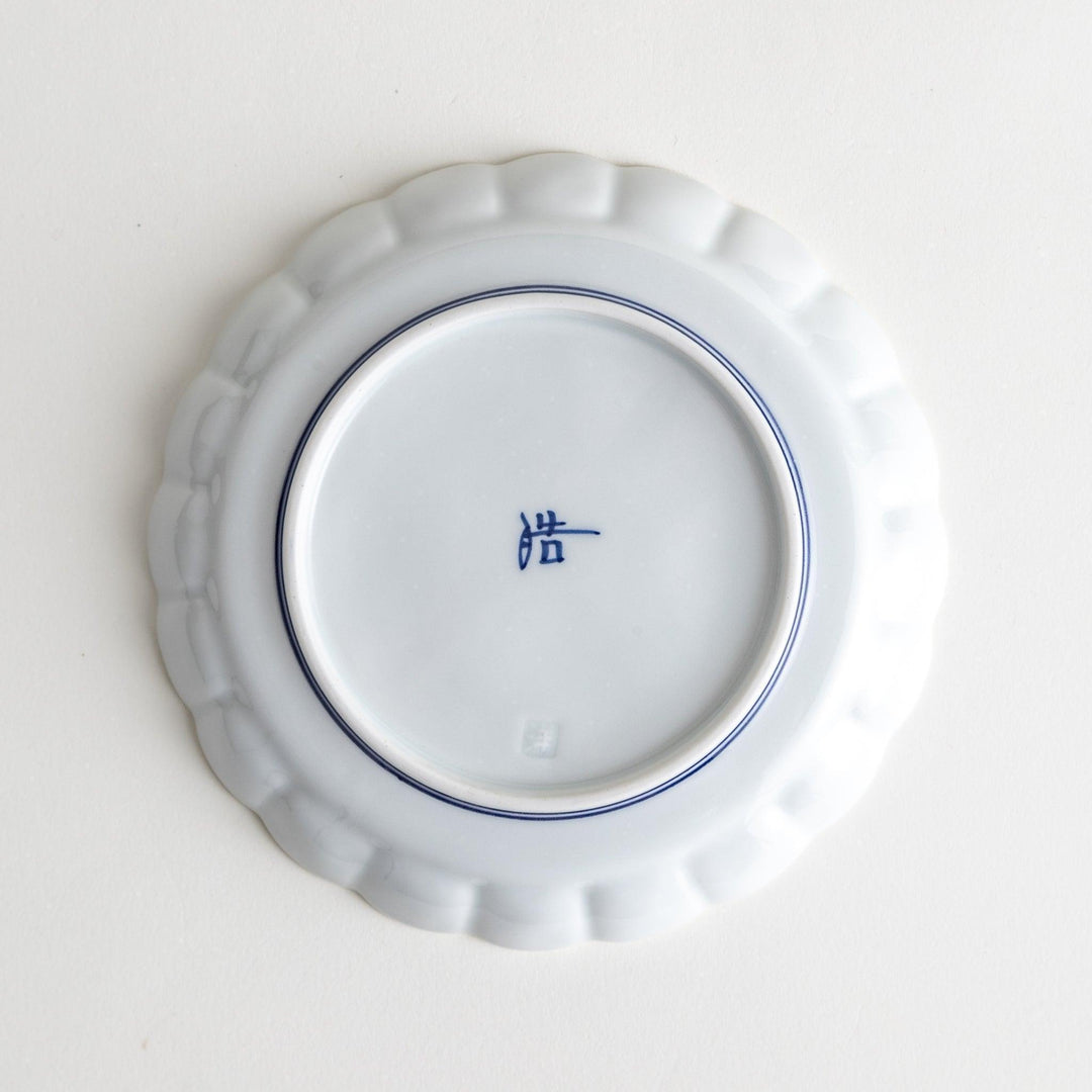 White dessert plate with scalloped edges, outlined in a thin blue or red line.