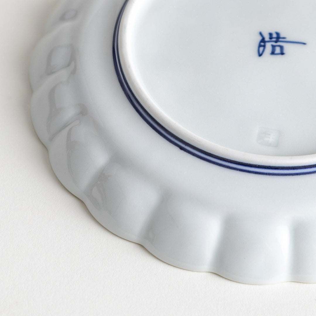 White dessert plate with scalloped edges, outlined in a thin blue or red line.