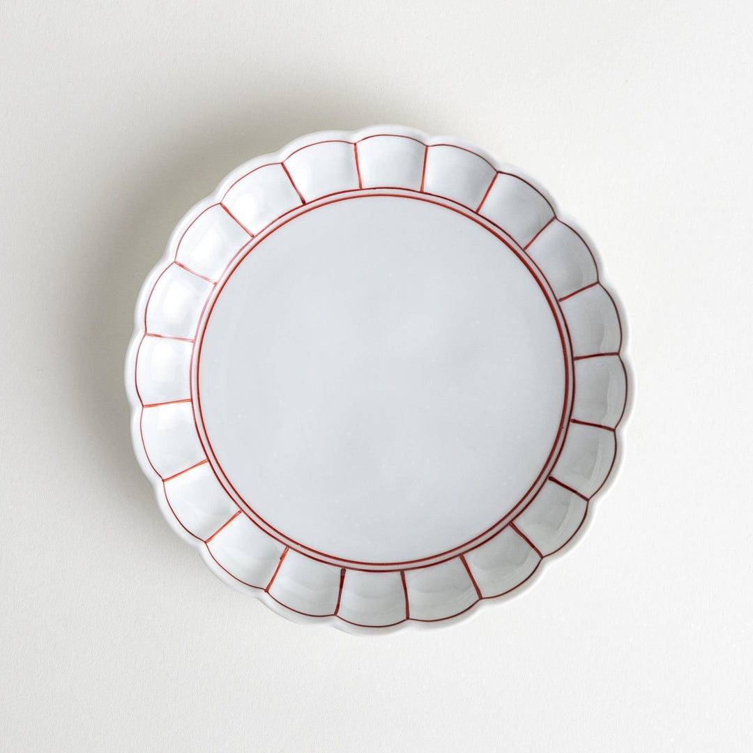 White dessert plate with scalloped edges, outlined in a thin blue or red line.
