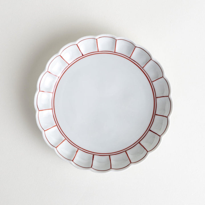 White dessert plate with scalloped edges, outlined in a thin blue or red line.