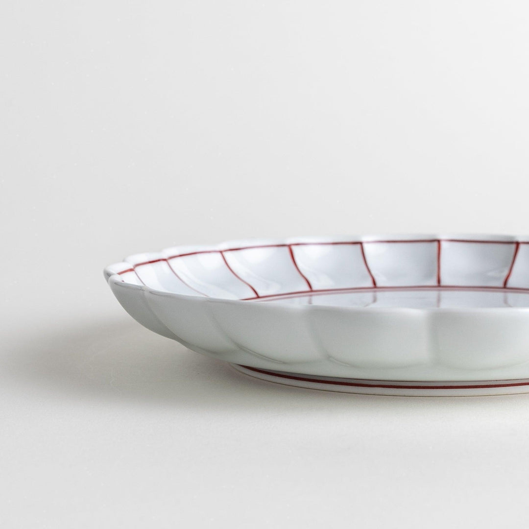 White salad plate with scalloped edges, outlined in a thin blue or red line.