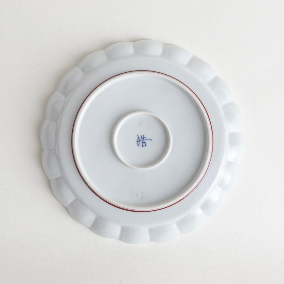 White salad plate with scalloped edges, outlined in a thin blue or red line.