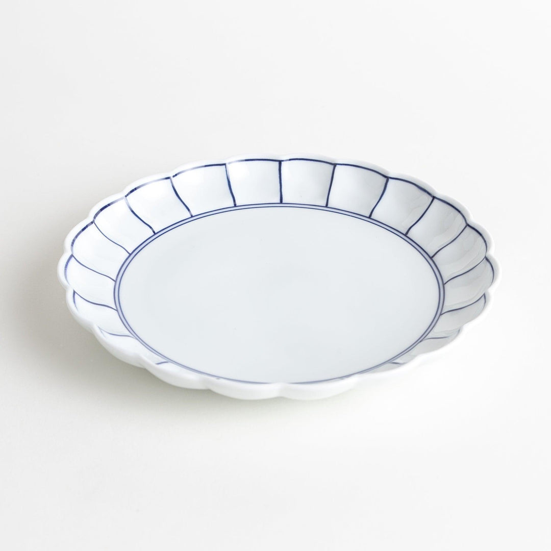 White salad plate with scalloped edges, outlined in a thin blue or red line.