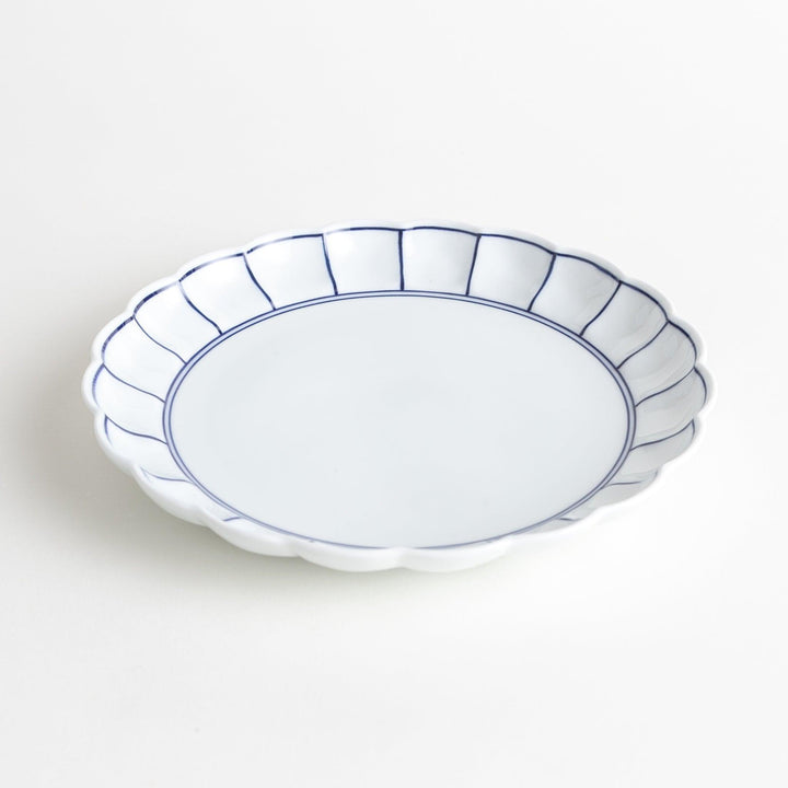 White salad plate with scalloped edges, outlined in a thin blue or red line.
