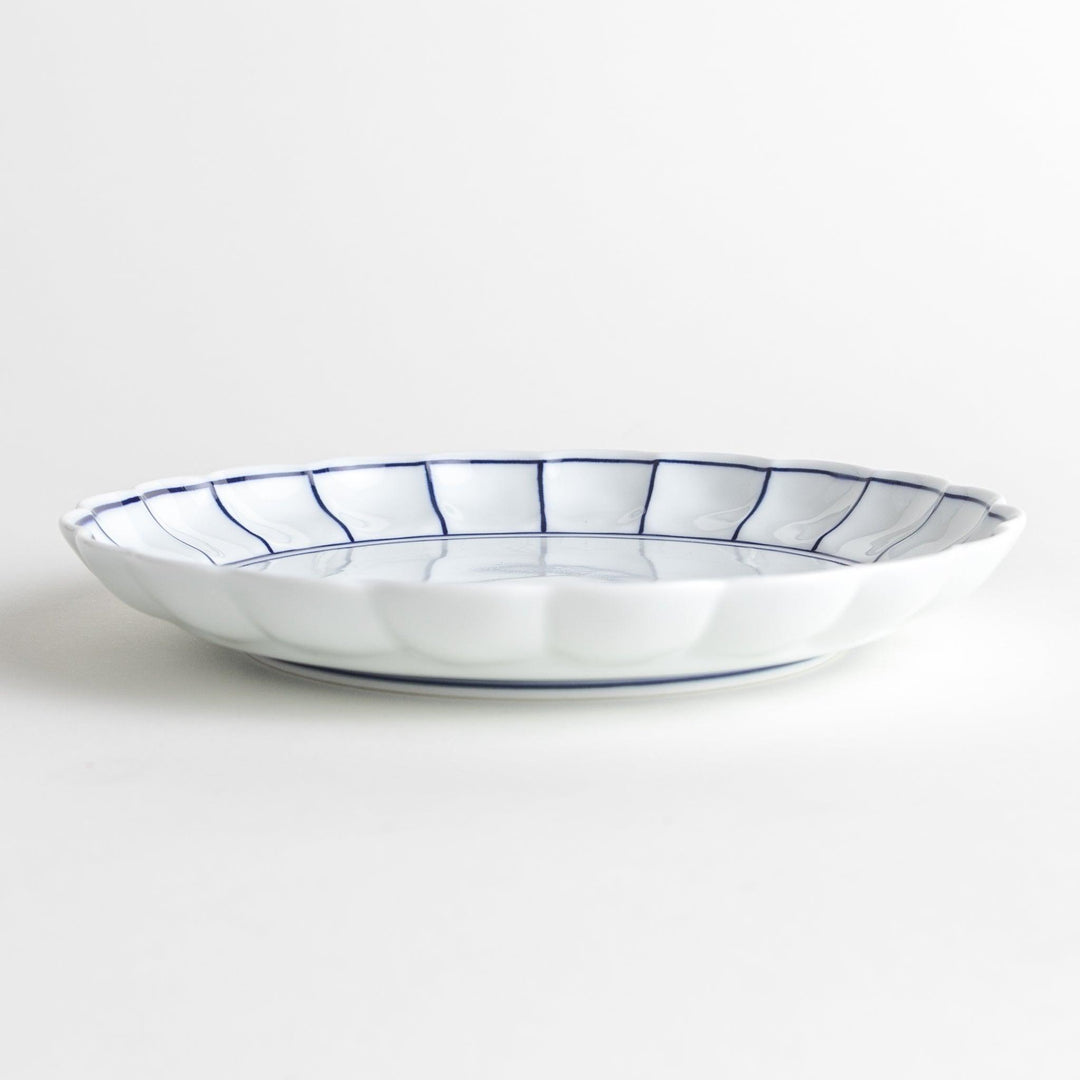 White salad plate with scalloped edges, outlined in a thin blue or red line.