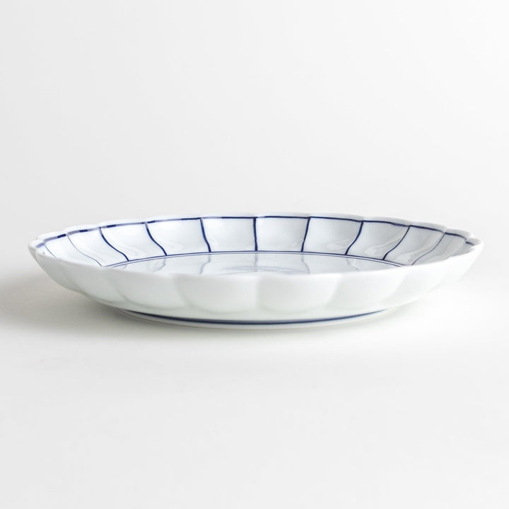 White salad plate with scalloped edges, outlined in a thin blue or red line.