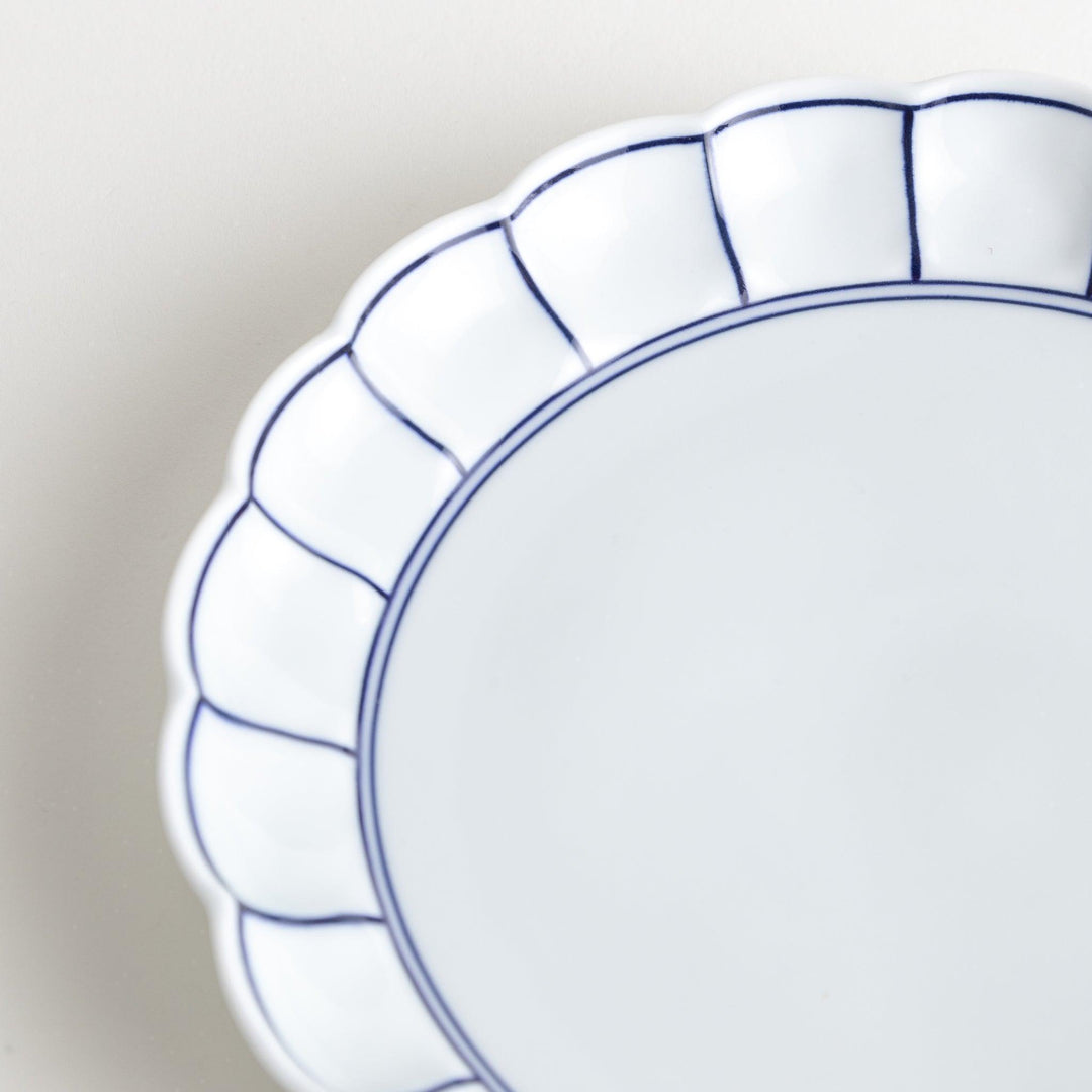 White salad plate with scalloped edges, outlined in a thin blue or red line.