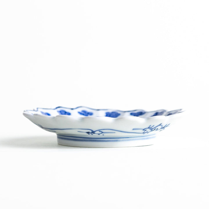 White plate with blue floral designs and a scalloped edge.

